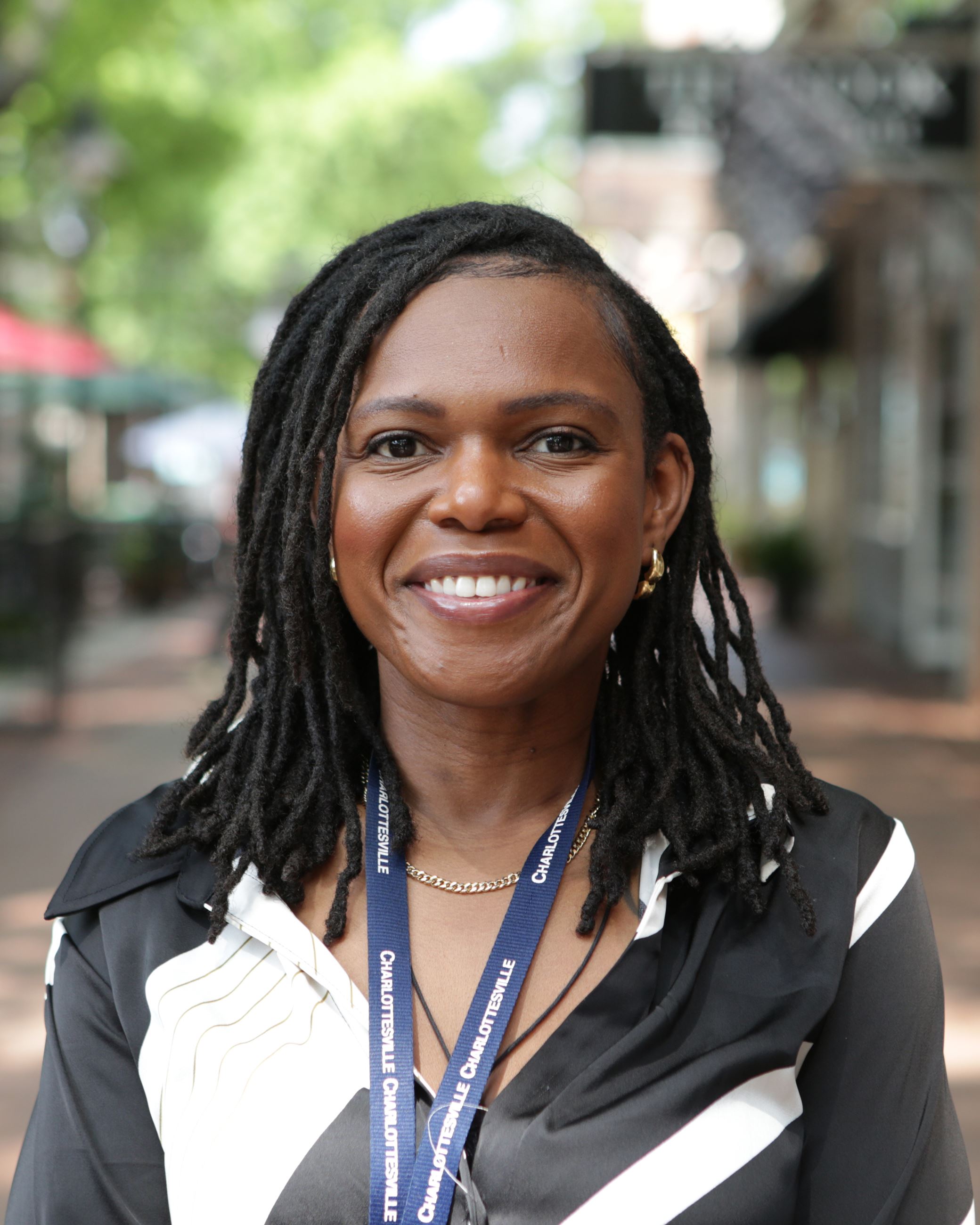 Ose Akinlotan in back and white dress with locs down and smiling